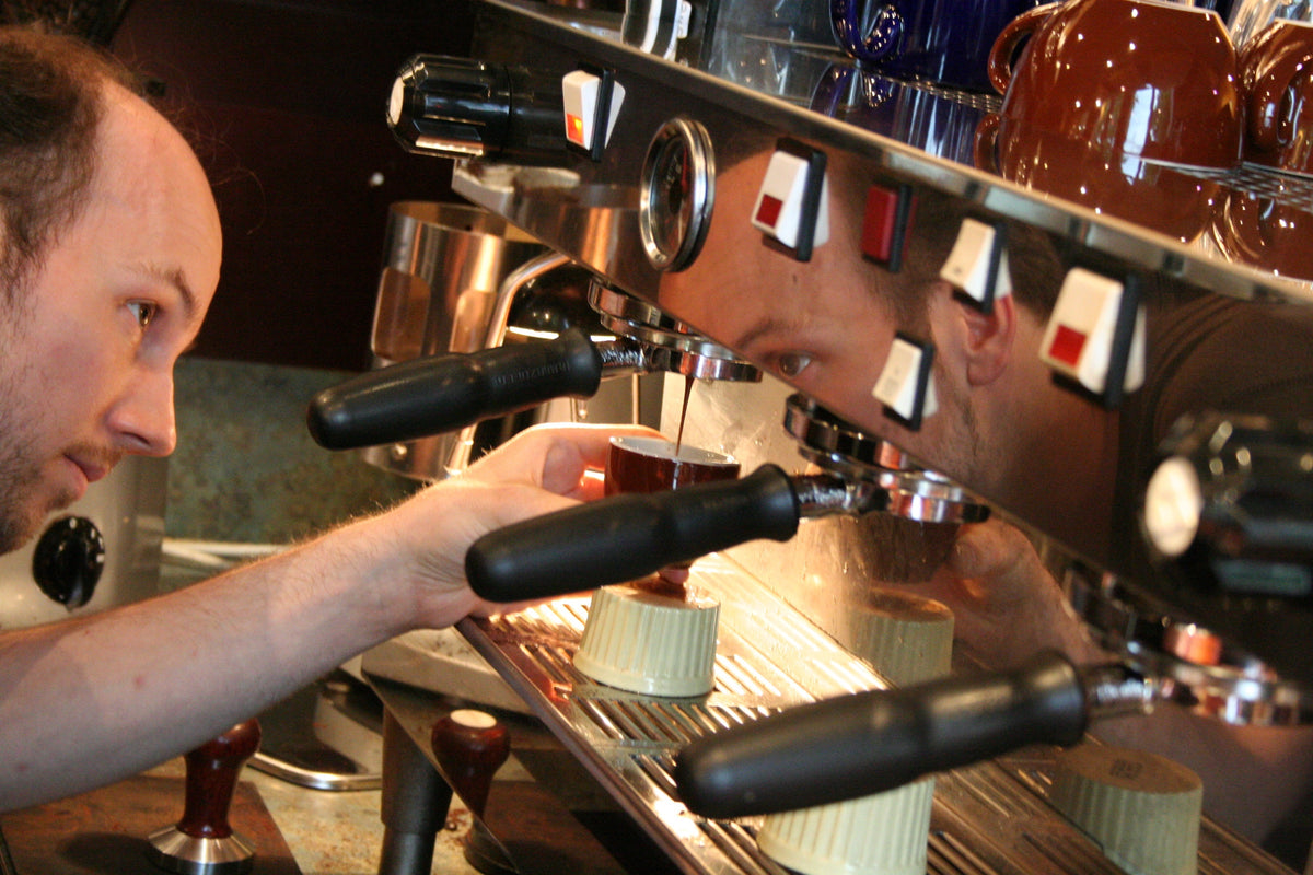 A barista watching an espresso shot pour at the first Elysian cafe, on West 5th Avenue