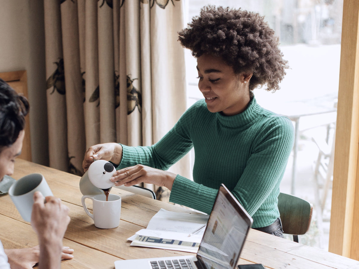 Pouring coffee for a colleague at a shared worktable