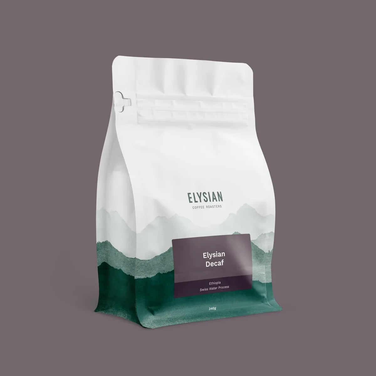 Elysian Decaf coffee bag, white with painted green mountains, on a muted purple background